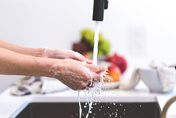 Hands being washed under a tap in a kitchen, promoting hygiene and cleanliness. HD wallpaper