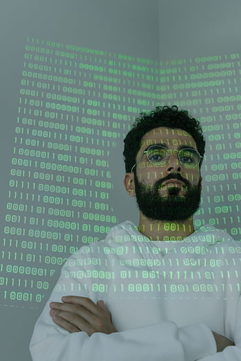 A bearded man in glasses stands with binary code projection, representing cybersecurity and digital intelligence. HD phone wallpaper