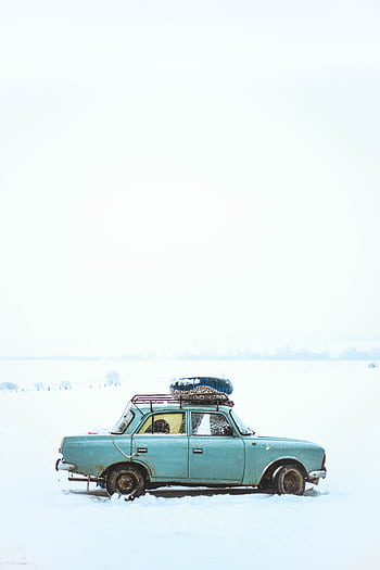 A vintage car parked in a snowy field in Kyrgyzstan, capturing the serene winter landscape. HD phone wallpaper
