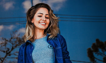 Portrait of a smiling young woman outdoors with a blue sky background. HD wallpaper