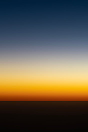 A tranquil sky with vibrant orange and blue gradient at sunset, offering a peaceful and serene atmosphere. HD phone wallpaper