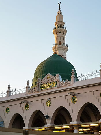 Detailed view of a mosque's green dome and minaret under the clear sky in Saudi Arabia. HD phone wallpaper