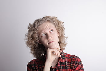 Pensive teenage boy with curly hair in studio, pondering ideas. HD wallpaper