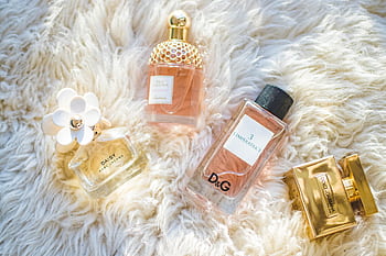 Elegant collection of perfume bottles on soft fur, highlighting luxury and style. HD wallpaper