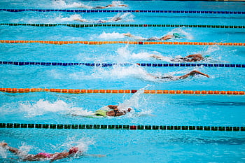 Swimmers compete in an outdoor pool race, showcasing athleticism and sportsmanship. HD wallpaper