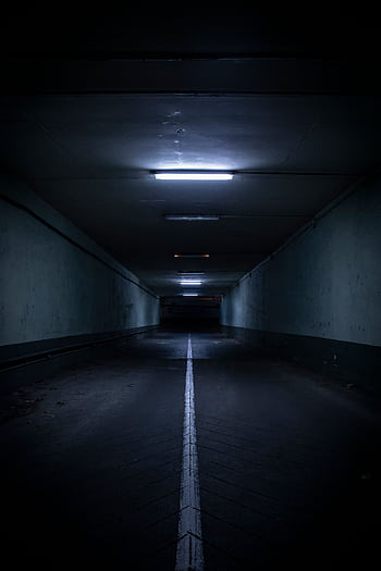 Moody view of a modern underground tunnel illuminated by fluorescent lighting, casting shadows. HD phone wallpaper
