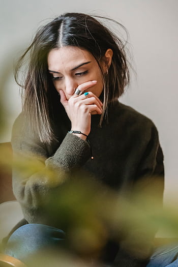 A young woman with short dark hair sits indoors, appearing deep in thought and contemplation. HD phone wallpaper