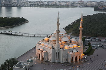 Stunning aerial view of Al Noor Mosque by the water at dusk in Sharjah, UAE. HD wallpaper
