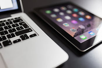 Close-up of a laptop and tablet on a black desk, showcasing modern technology essentials. HD wallpaper