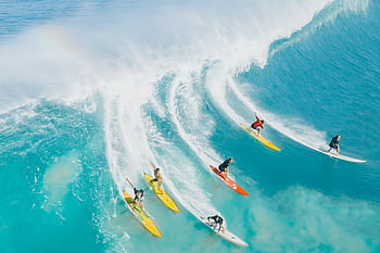 A dynamic shot of surfers riding a big wave at Waimea Bay, Hawaii. Ideal for sports and adventure themes. HD wallpaper
