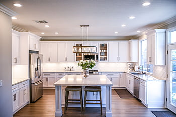 Spacious and elegant kitchen featuring white cabinetry, island, and stainless steel appliances. HD wallpaper