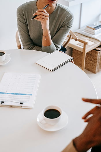 A focused and formal professional consultation session at a round table with coffee and documents. HD phone wallpaper