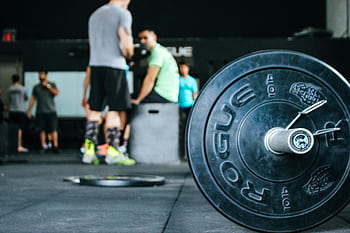 Energetic gym environment showcasing weightlifting equipment and active individuals. HD wallpaper