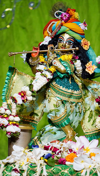 Vibrant Krishna statue adorned with flowers and traditional attire, captured in a ceremonial setting. HD phone wallpaper