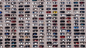 Top-down aerial shot of a large parking lot filled with rows of cars, showcasing organized symmetry. HD wallpaper