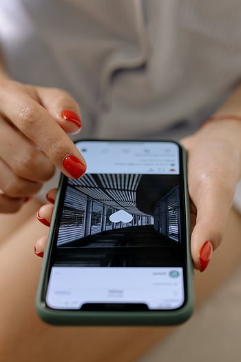 A woman with red nails uses a smart to browse social media indoors. HD phone wallpaper