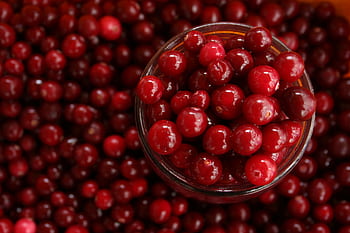 Close-up of vibrant cranberries in a glass bowl, perfect for healthy recipes. HD wallpaper