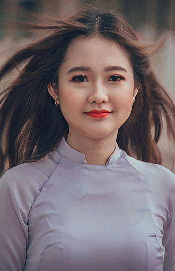 Close-up portrait of a young woman with flowing hair and traditional attire, exuding elegance and confidence. HD phone wallpaper