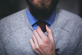 A close-up of a man adjusting his tie, showcasing professional and business attire. HD wallpaper
