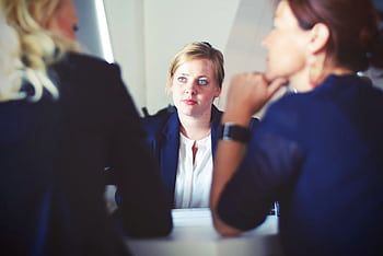 Focused discussion during a business meeting featuring three women. HD wallpaper