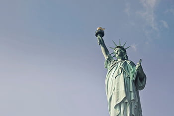 Low angle view of the Statue of Liberty against a clear blue sky, symbolizing dom in New York. HD wallpaper