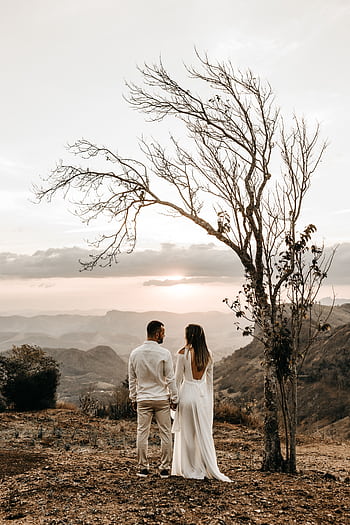 A romantic couple stands lovingly together at sunset with a breathtaking mountain view. HD phone wallpaper