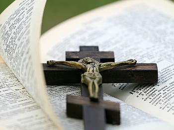 An open Bible with a brass crucifix on a dark wooden cross lying across it. HD wallpaper