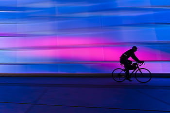 A cyclist's silhouette zooms past a colorful urban background. Ideal for fitness and city life themes. HD wallpaper