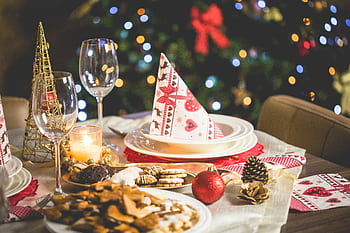 Beautifully set Christmas table with decorations, food, and drinks under festive lights. HD wallpaper