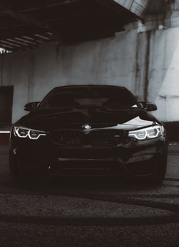 Front view of a black BMW M4 car parked under dim lighting for a bold and stylish appearance. HD phone wallpaper