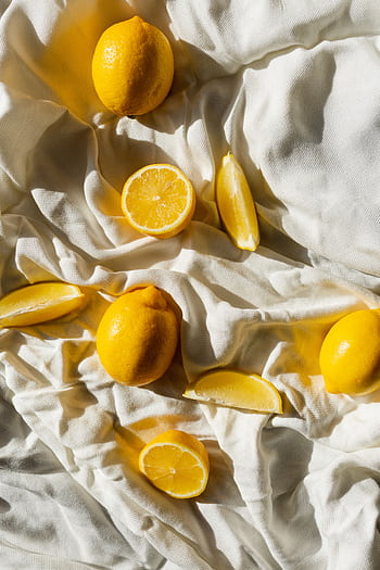 Bright lemons scattered on white fabric, capturing natural sunlight and freshness. HD phone wallpaper