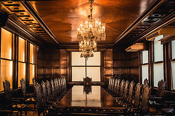 Luxury dining room featuring a grand chandelier, wooden table, and ornate chairs. HD wallpaper