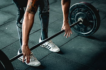 Focused athlete preparing to lift a heavy barbell. Indoor gym setting. HD wallpaper