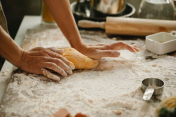 A person kneads fresh dough in a kitchen, showcasing the baking process. HD wallpaper
