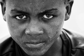 Close-up black and white portrait capturing intense facial expression of a young boy. HD wallpaper