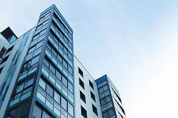 Low-angle view of a modern glass skyscraper against a clear sky in Poole, UK. HD wallpaper