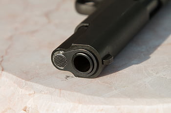 Detailed close-up of a gun barrel resting on a marble surface, highlighting the metal texture. HD wallpaper