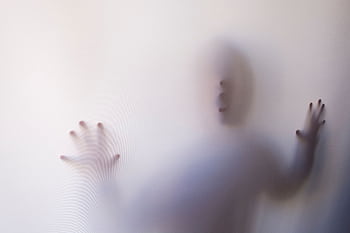 Eerie silhouette of a person pressing against a white curtain, creating a mysterious atmosphere. HD wallpaper