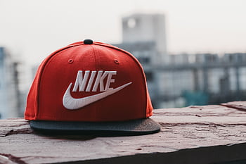 Red cap with logo on a rooftop against an urban cityscape backdrop in daylight. HD wallpaper