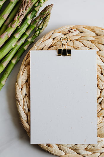 Top view of fresh asparagus next to a blank note on a woven mat. Perfect for culinary themes. HD phone wallpaper
