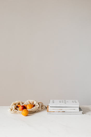 Simple still life of apricots in a sack with stacked books on a white table. HD phone wallpaper