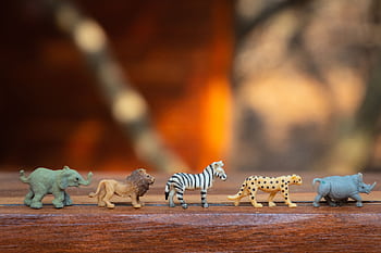 Miniature toy animals in a row on wood, displaying various wild species. HD wallpaper