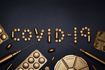 Creative COVID-19 concept with gold pills and syringes arranged on a dark background. HD wallpaper