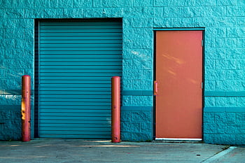 Vivid blue wall with a closed door and shutter in Valparaiso's urban setting. HD wallpaper