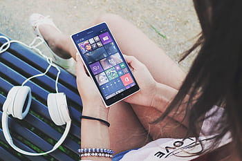 Close-up of a woman using a Windows smart with heads outdoors. HD wallpaper