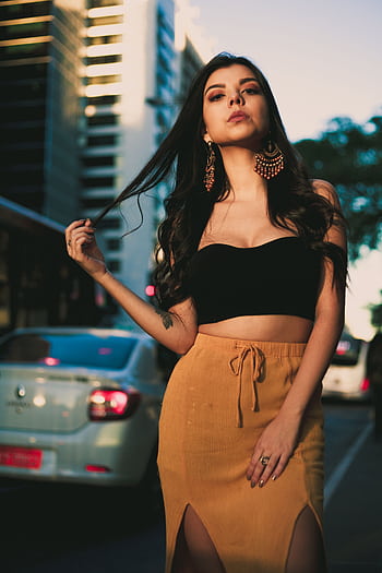Chic portrait of a young woman in urban setting wearing a crop top and stylish earrings. HD phone wallpaper