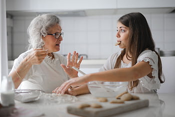 Grandmother and granddaughter bonding over baking cookies in a cozy kitchen. HD wallpaper