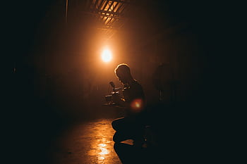 Silhouette of a cinematographer operating a camera in a dimly lit studio with dramatic lighting. HD wallpaper