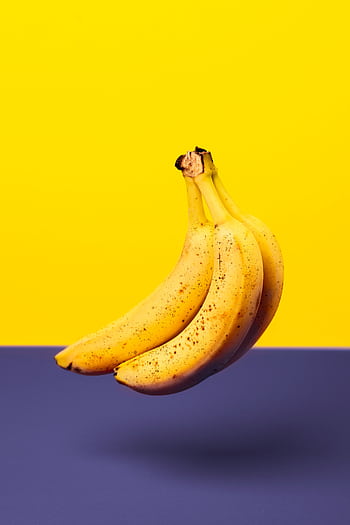 A bunch of fresh bananas isolated against a vibrant yellow and purple background. HD phone wallpaper