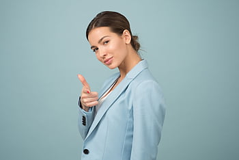 A young woman in a blue suit exhibits confidence with a relaxed pose against a blue background. HD wallpaper